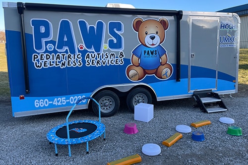 PAWS Mobile Sensory Trailer Exterior with a trampoline and obstacles to play on sitting outside of it